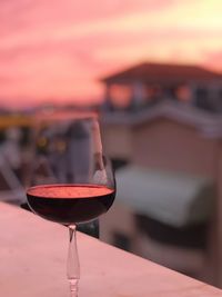 Close-up of wineglass on table against sky during sunset