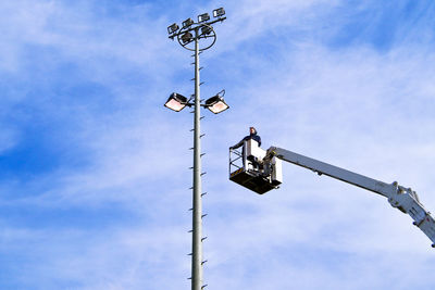 Low angle view of men working against sky