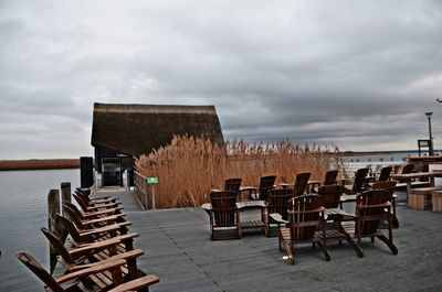 Empty chairs and tables against sky in sea