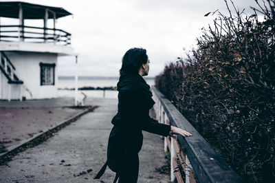 Woman standing by railing against sea