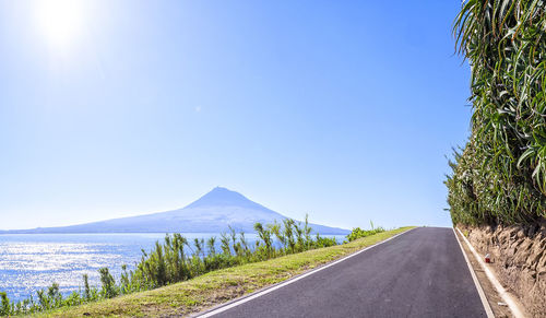 Road by mountains against clear blue sky