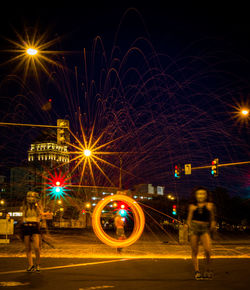 Women standing by wire wool on street at night