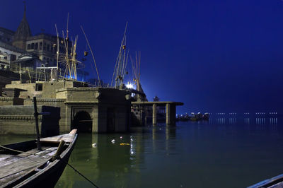 Sailboats moored on river against sky at night