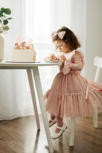 Cute little girl eats a birthday cake with a spoon on her birthday