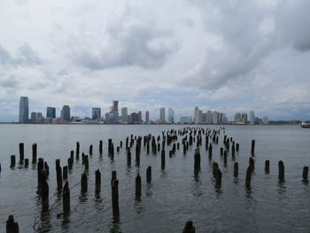 Wooden posts in sea against sky