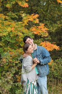 Full length of a smiling young woman standing by plants