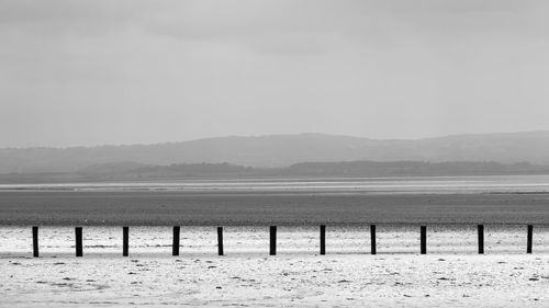 Wooden posts on beach against sky