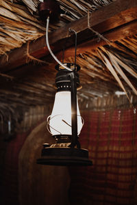 Low angle view of illuminated light bulb hanging from ceiling