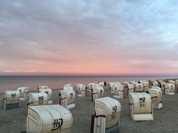 Hooded chairs on beach against cloudy sky