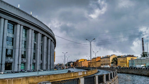 Bridge over river by buildings in city against sky