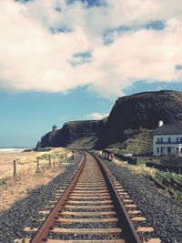 Railroad track against cloudy sky