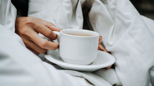 Midsection of man holding coffee cup