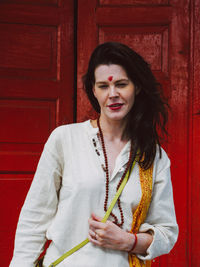 Portrait of woman standing against red door