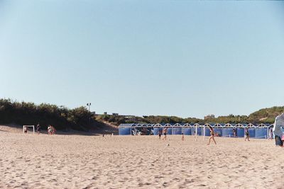 People enjoying on beach against clear sky