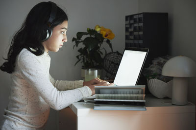 Girl doing homework with laptop