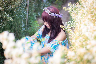 Midsection of woman with pink flowering plants against trees