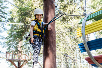 Low angle view of man standing on rope against trees