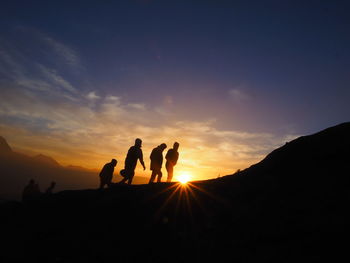 Silhouette people standing on mountain against sky during sunset