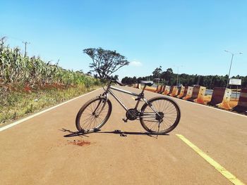 Bicycle parked on road during sunny day