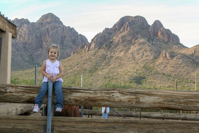 Portrait of cute girl sitting on fence