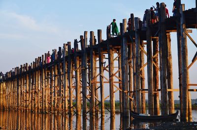 Wooden posts on pier over lake against sky