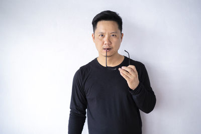 Portrait of young man standing against white background