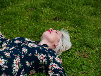 High angle view of mature woman lying on grassy field