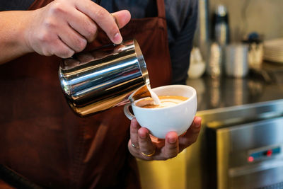 Cropped image of man holding teapot and coffee cup