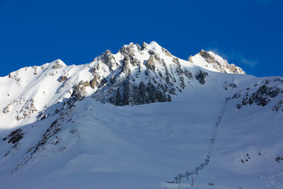 Scenic view of snowcapped mountains against blue sky