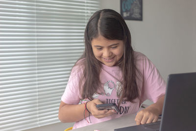 Girl looking away while standing on laptop