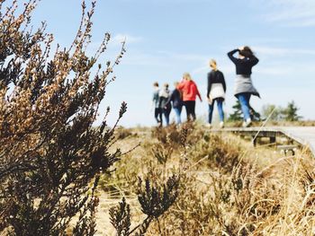 Rear view of people walking on boardwalk against sky