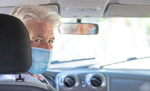 Portrait of senior man wearing mask sitting in car