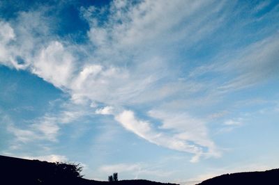 Low angle view of silhouette trees against blue sky