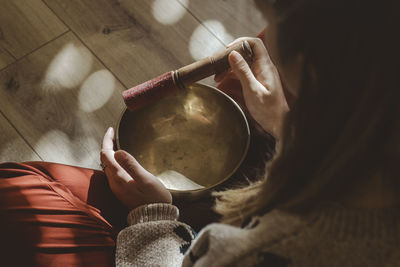 Midsection of woman holding tibetan bowl for meditation 