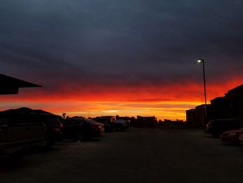 Cars on illuminated road against sky at sunset