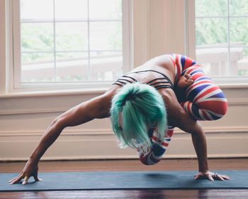 Full length of woman stretching against window