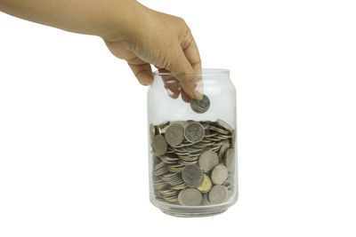 Close-up of hand holding coin against white background