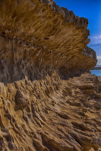 Rock formation on beach against sky