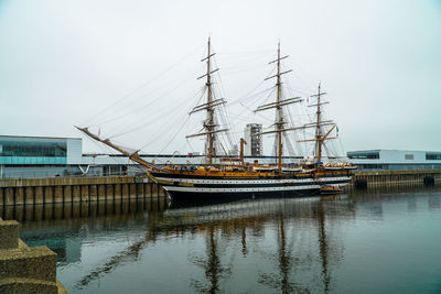 Boats moored at harbor against clear sky