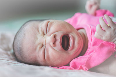 Baby girl crying while lying on bed