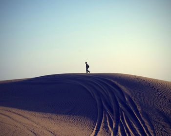 Distant image of man walking on sand dune