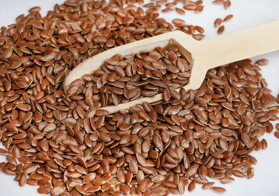 Linseed with wooden scoop on raw wooden table