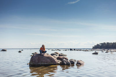 People sitting on sea against sky