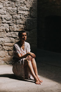 Portrait of young woman sitting on wall