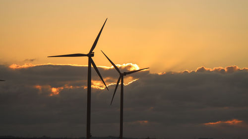 Low angle view of wind turbine against sky during sunset