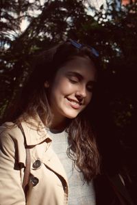 Smiling young woman against trees