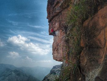 Scenic view of mountain climber against cloudy sky