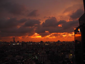 Cityscape against dramatic sky during sunset