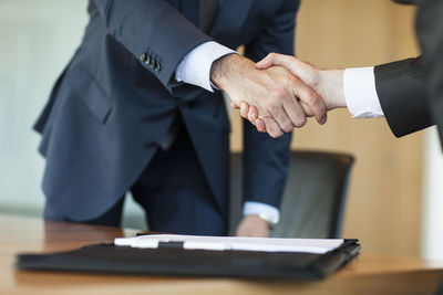 Low section view of man holding hands on table