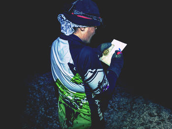 Side view of man standing against black background